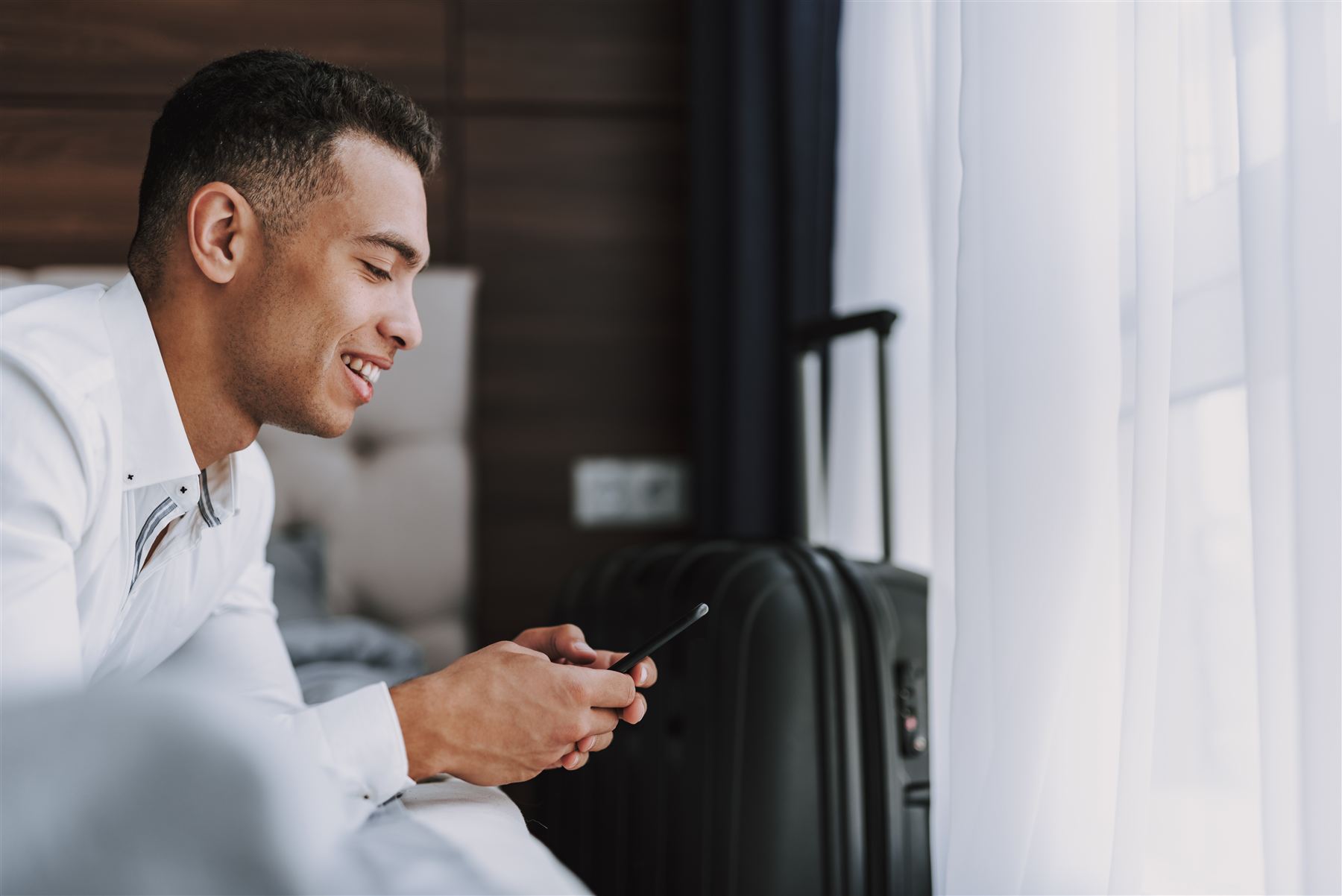 A reader smiling at his phone in a hotel room